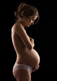Young pregnant woman over black background