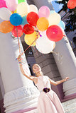 beautiful lady in retro outfit holding a bunch of balloons on th