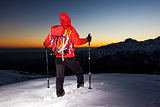 Winter hiking: man stands on a snowy ridge looking at the sunset