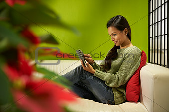 Asian girl with touch pad relaxing on sofa at home