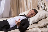 Elegant playboy reclining on a bed