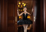 Ballerina in black tutu standing in doorway