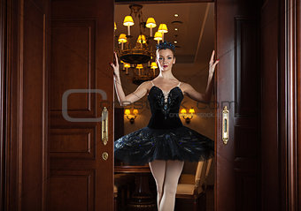 Ballerina in black tutu standing in doorway