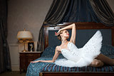 Ballerina lying down on bed and daydreaming in luxury interior