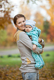 Portrait of young woman and her baby son in autumn park