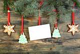Card and Christmas cookies on fir branches.