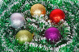 Five Christmas colored balls on the green tinsel