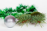 Silvery ball, pine branch and green Christmas tinsel