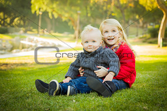 Little Girl with Baby Brother Wearing Coats at the Park 