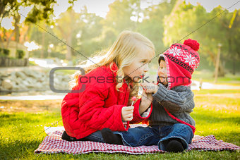 Little Girl with Baby Brother Wearing Coats and Hats Outdoors 