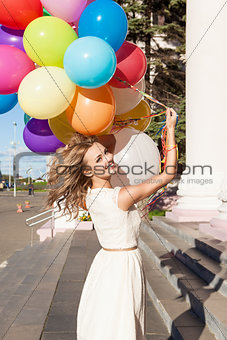 beautiful lady in retro outfit holding a bunch of balloons on th