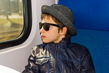 Handsome boy in sunglasses rides on a train