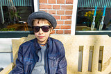 Boy with glasses sitting on a bench in front of the house, The N