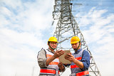two workers standing before electrical power tower