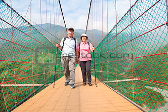 happy senior couple walking on bridge in nature park