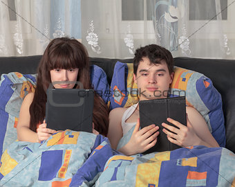 Young couple using tablet PC in their bed