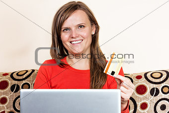 Young woman smiling and  using her credit card for online shoppi