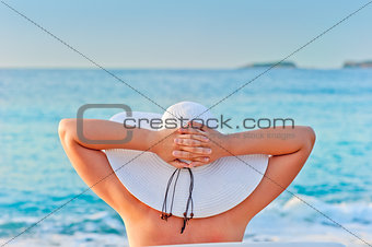 woman takes a sunbath in white hat near the sea