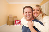 Couple in New House with Boxes and Sold Sale Sign