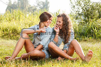 two girlfriends sitting on grass