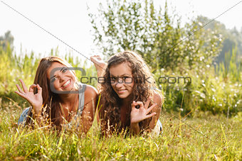 two girlfriends lying down on grass
