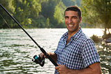 portrait of man fishing on river and holding rod