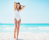 Full length portrait of happy young woman relaxing on beach