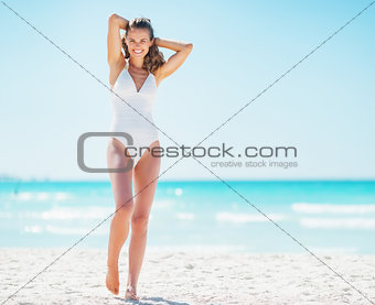 Full length portrait of happy young woman relaxing on beach