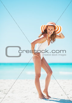 Full length portrait of young woman in hat on beach