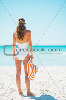 Happy young woman with hat on beach. rear view