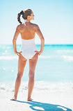 Full length portrait of young woman standing on beach. rear view