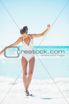 Full length portrait of young woman walking on sea coast