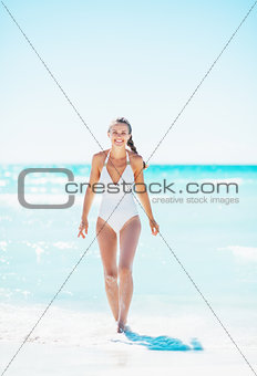 Full length portrait of young woman walking out on sea coast