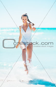Happy young woman playing with water at seaside
