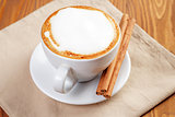 cup of freshly made cappuccino with cinnamon sticks