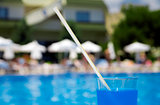 cocktail in glass on a background tourist resort and blue water of pool