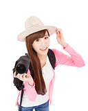 smiling young woman holding a camera and hat