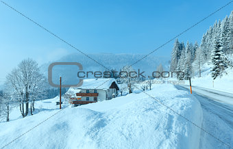 Morning winter misty rural alpine road and house