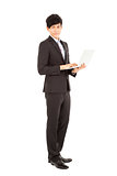Full length of  young businessman standing with laptop