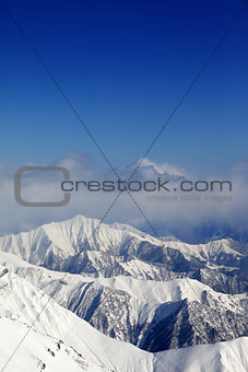 Winter snowy mountains and blue sky with clouds