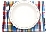 The knife, fork and white plate on a colorful napkin on a white 