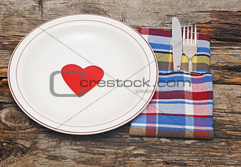 Empty dish, knife and fork and colorful napkin on wood table 