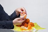 Female hands husk tangerines