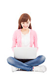 Smiling young woman sitting and using a laptop