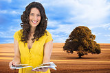 Composite image of cheerful curly haired brunette reading magazine