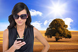 Composite image of happy brunette using smartphone