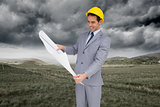 Composite image of smiling architect with hard hat looking at plans