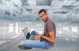 Composite image of man wearing glasses sitting on floor using laptop and looking at camera