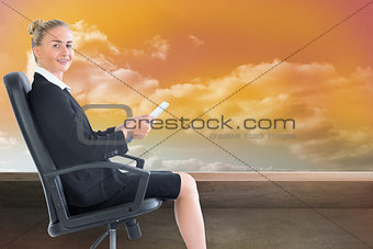 Composite image of businesswoman sitting in swivel chair holding folder