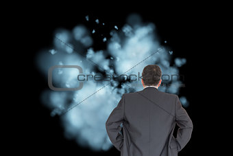 Composite image of businessman standing back to the camera with hands on hip
